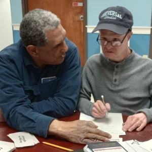 Cushing adult with teacher at desk at LOU program