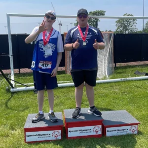 two Special Olympics athletes posing for photos on podium